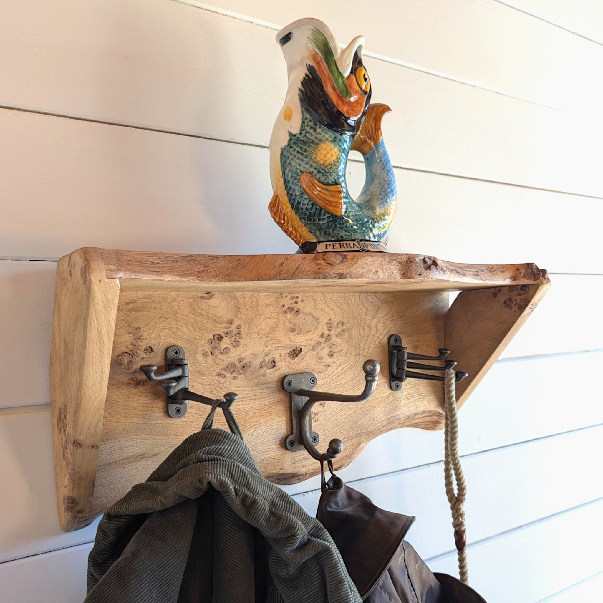 Thriverton live edge pippy oak coat rack and shelf with cast iron hooks mounted on a white shiplap wall