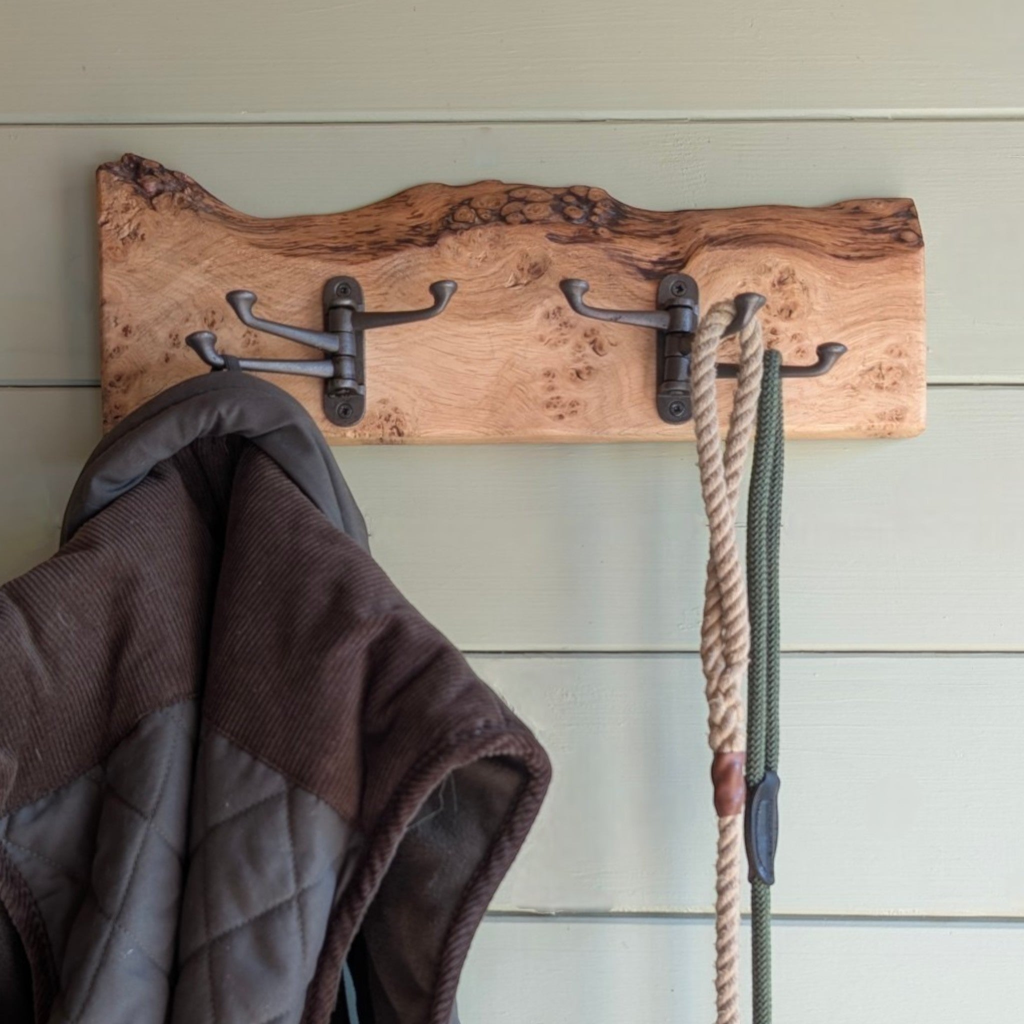 Thriverton hand-crafted Pippy Oak coat rack with live-edge wood and cast-iron hooks mounted on a green wall