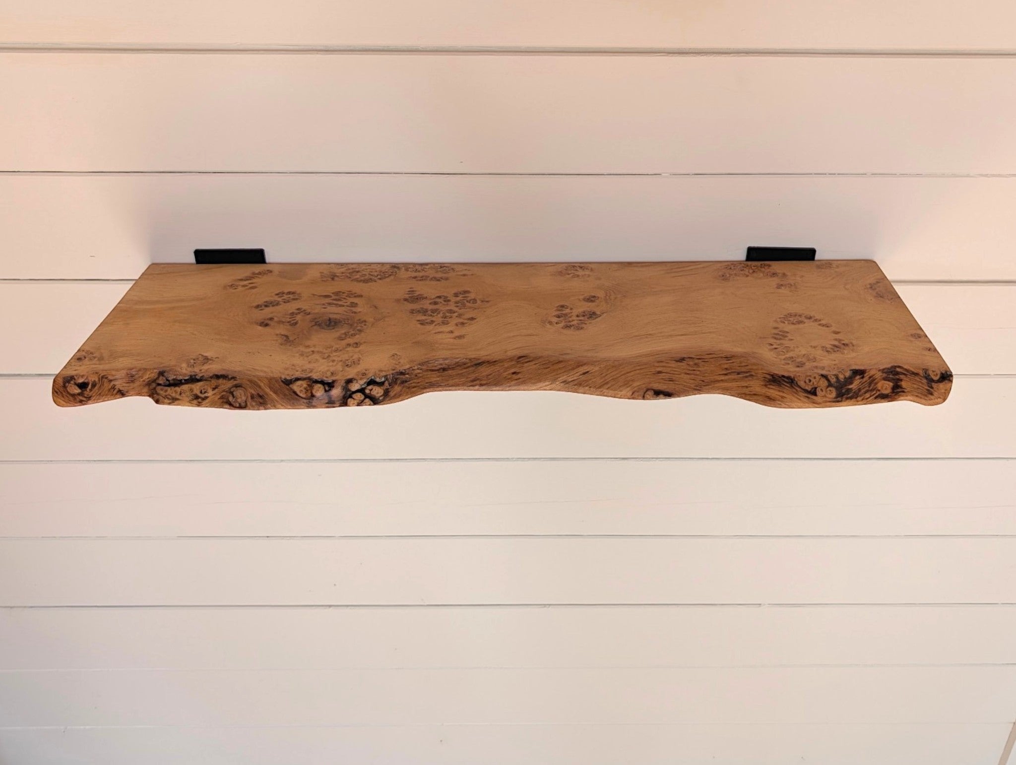 Thriverton hand-crafted pippy oak shelf with a natural live-edge profile and black cast-iron brackets on white wall