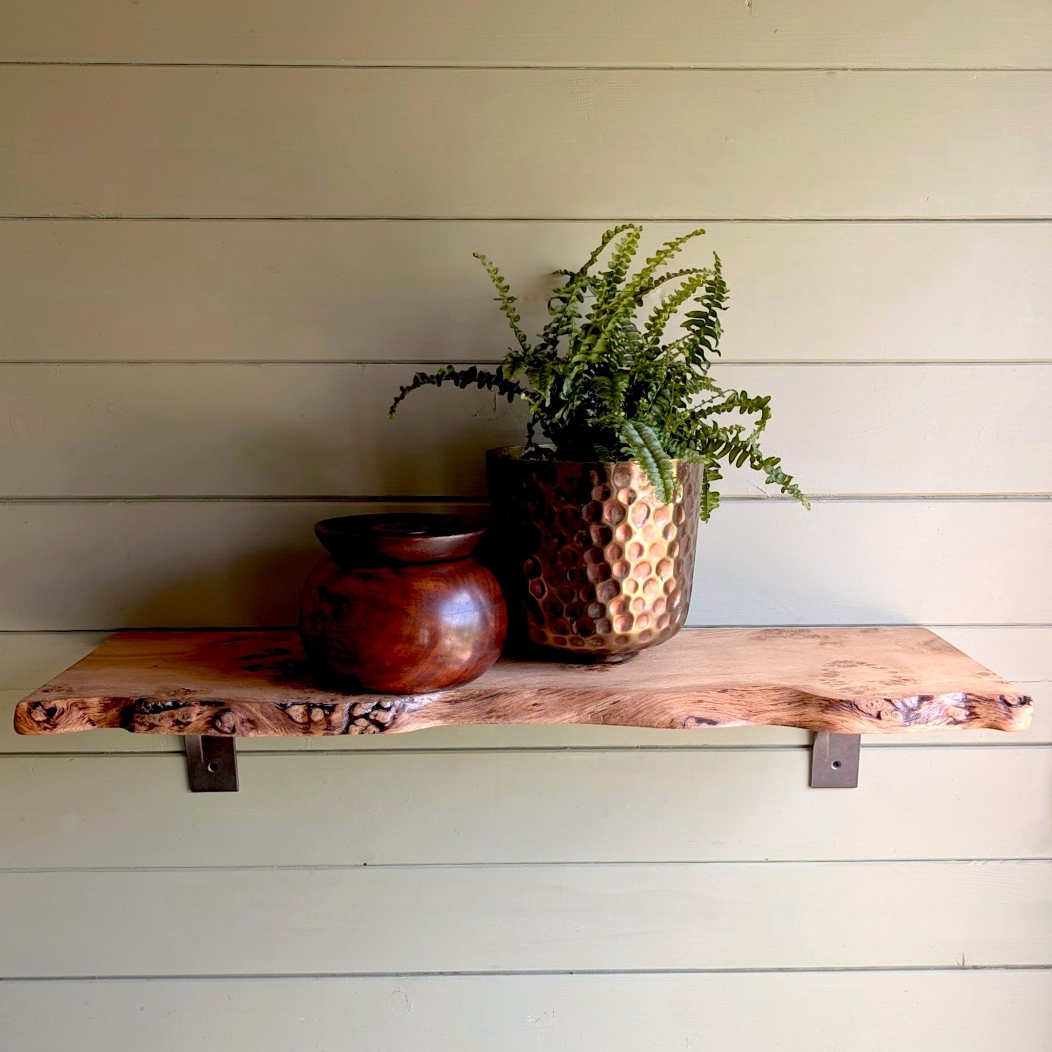 Thriverton hand-crafted pippy oak live edge shelf with natural wood grain and cast-iron brackets on a panelled wall.